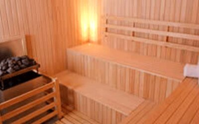 Wooden sauna with tiered benches, stone heater and folded white towels at Design Suites Buenos Aires.