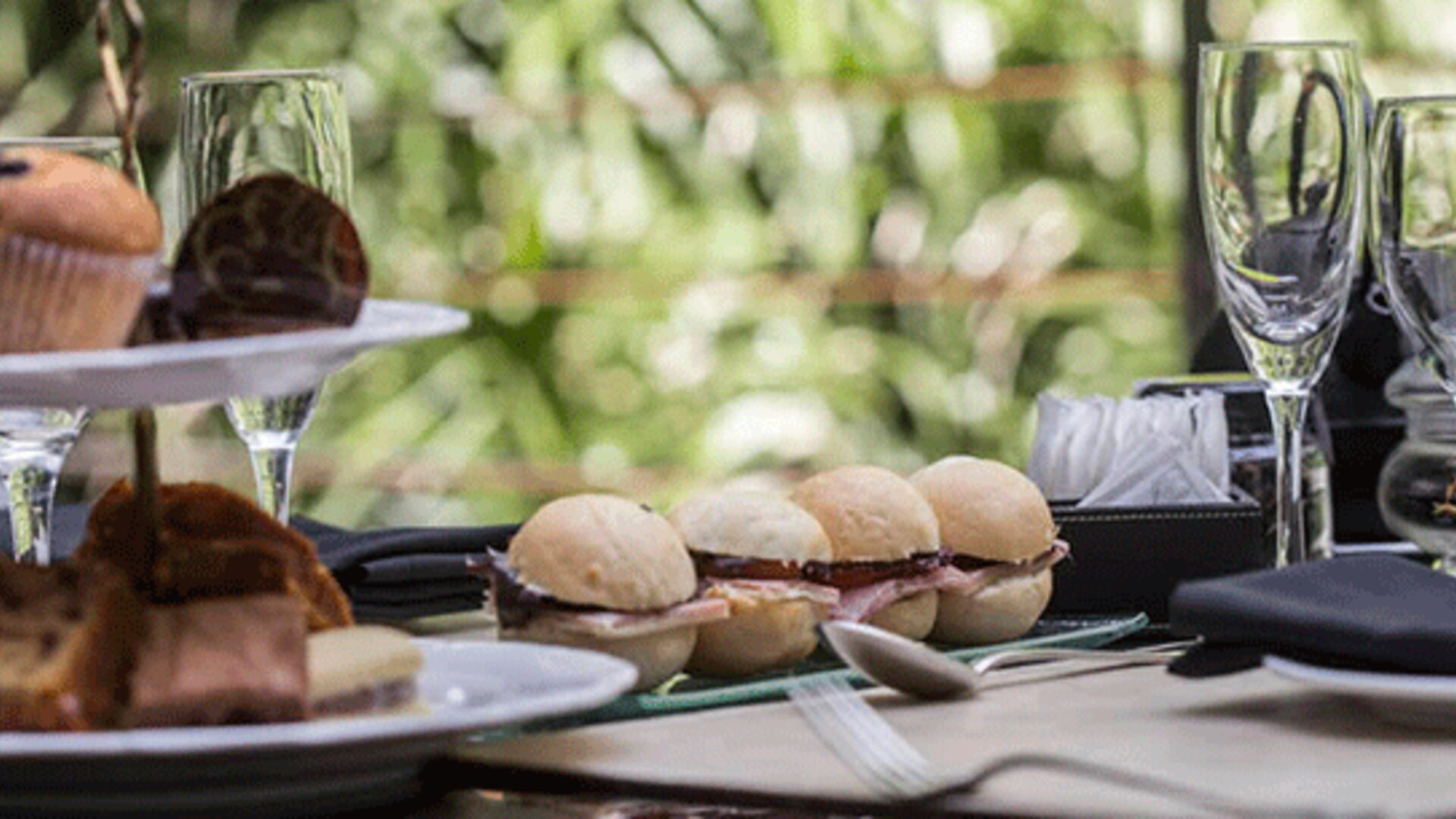 Table set with pastries, bread rolls, glassware and folded napkins against a leafy backdrop at Design Suites Buenos Aires.