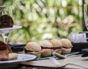 Table set with pastries, bread rolls, glassware and folded napkins against a leafy backdrop at Design Suites Buenos Aires.
