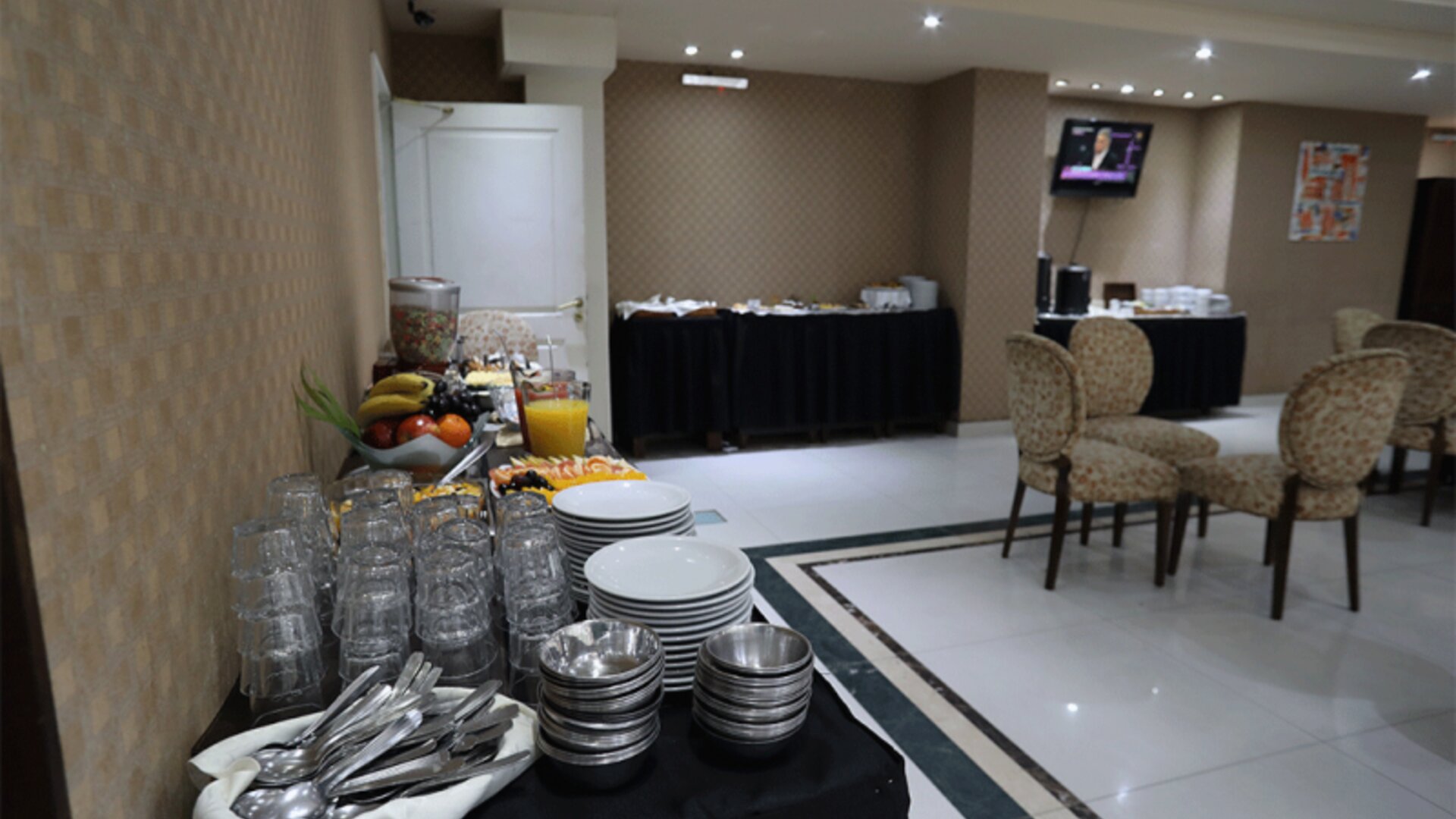 Breakfast buffet with stacked plates, glasses, cutlery, fresh fruit, juice and serving tables at HR Esmeralda Luxor.