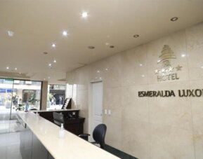 Hotel reception with marble counter, black workstation and wall-mounted HR Hotel Esmeralda Luxor signage.
