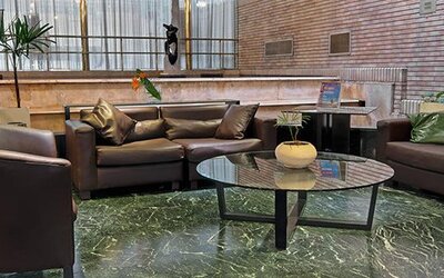 Lounge with dark leather sofas, armchairs, glass coffee table and green marble flooring at Hotel Regente Palace.
