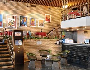 Reception area with black front desk, staircase, brick walls and small round tables with chairs at Hotel Regente Palace.