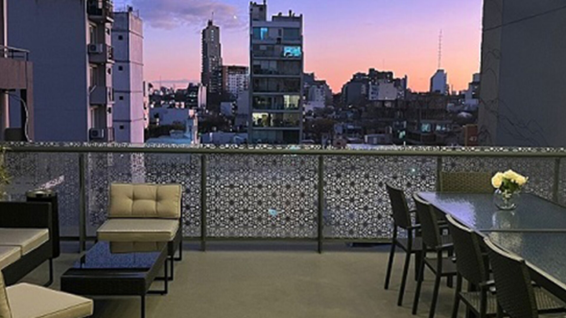 Rooftop terrace with lounge seating, dining table and city skyline views at sunset at Ian Hotel.