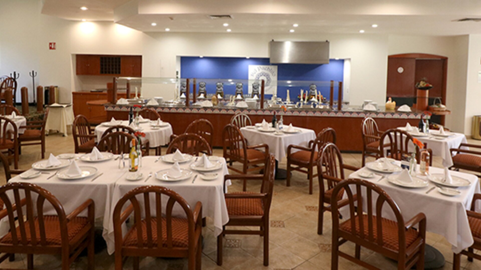 Restaurant with tables, wooden chairs, white tablecloths and decorative floral centrepieces at Hotel Misión Toreo Centro De Convenciones.