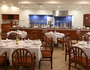 Restaurant with tables, wooden chairs, white tablecloths and decorative floral centrepieces at Hotel Misión Toreo Centro De Convenciones.