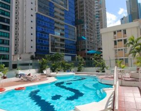 Outdoor swimming pool with turquoise water, sun loungers, palm trees and surrounding high-rise buildings at Hospedium Princess Hotel Panamá.