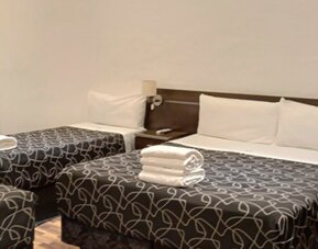 Guest room with one double bed and two single beds, patterned black bedding, white towels and dark bedside furniture at Bagu Buenos Aires.