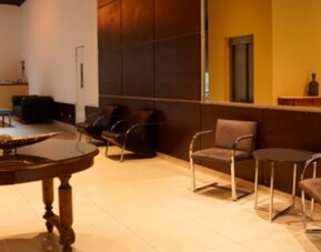 Lobby seating area with upholstered chairs, round tables, decorative bowl and warm yellow walls at Bagu Buenos Aires.