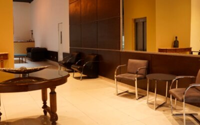 Lobby seating area with upholstered chairs, round tables, decorative bowl and warm yellow walls at Bagu Buenos Aires.