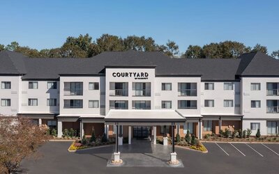 Exterior view of the Courtyard by Marriott hotel building with covered entrance, landscaped grounds and parking spaces at Courtyard By Marriott Dothan.