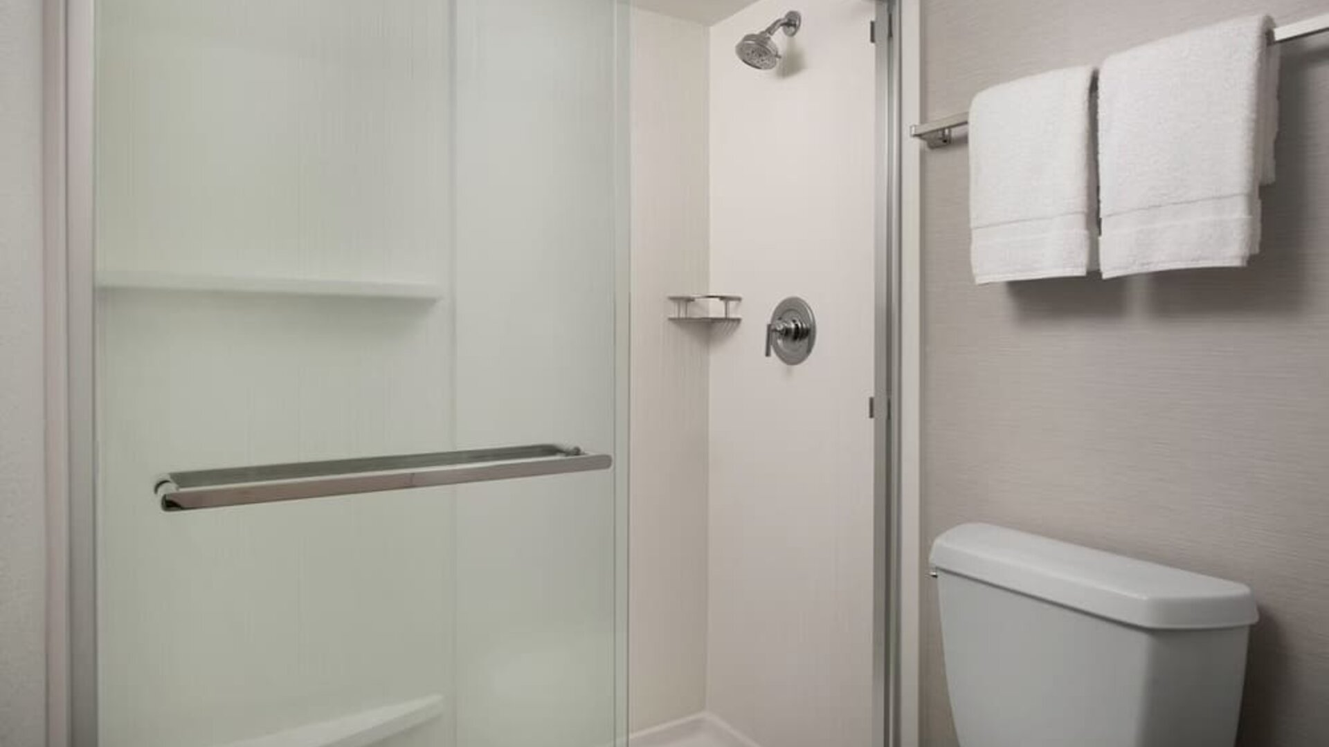 Bathroom with glass-enclosed walk-in shower, white toilet, gray walls and white towels hanging on a rail at Courtyard By Marriott Dothan.