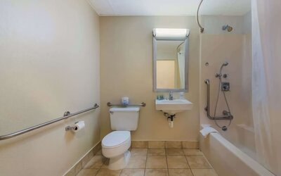 Accessible bathroom with roll-in shower, grab rails, toilet and wall-mounted sink at Best Western Executive Hotel Of New Haven-West Haven.