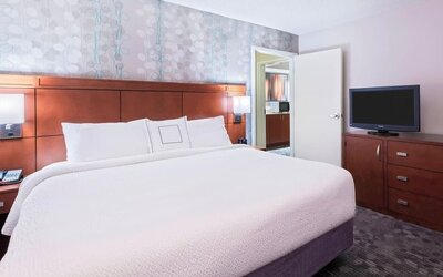 Guest room with king bed, white bedding, wooden headboard, bedside lamps and television at Courtyard By Marriott Sarasota Bradenton Airport.