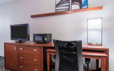 n-room workspace with wooden desk, office chair, television, microwave and decorative shelving at Courtyard By Marriott Sarasota Bradenton Airport.