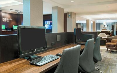 Business centre with desktop computers, keyboards, office chairs and a shared wooden work counter at Courtyard By Marriott Sarasota Bradenton Airport.