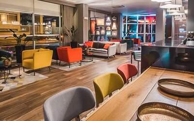 Hotel lounge and bar seating with colourful armchairs, sofas, pendant lights and a long communal table at Novotel Lima San Isidro.