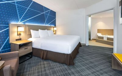 Day use king suite with comfortable bed, sofa and private bathroom with tub at Comfort Inn & Suites Barrie. 