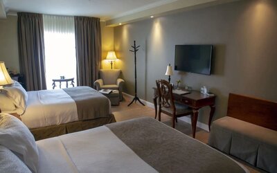 Twin day use room with TV, work desk and lounge seating at Hotel Brossard.