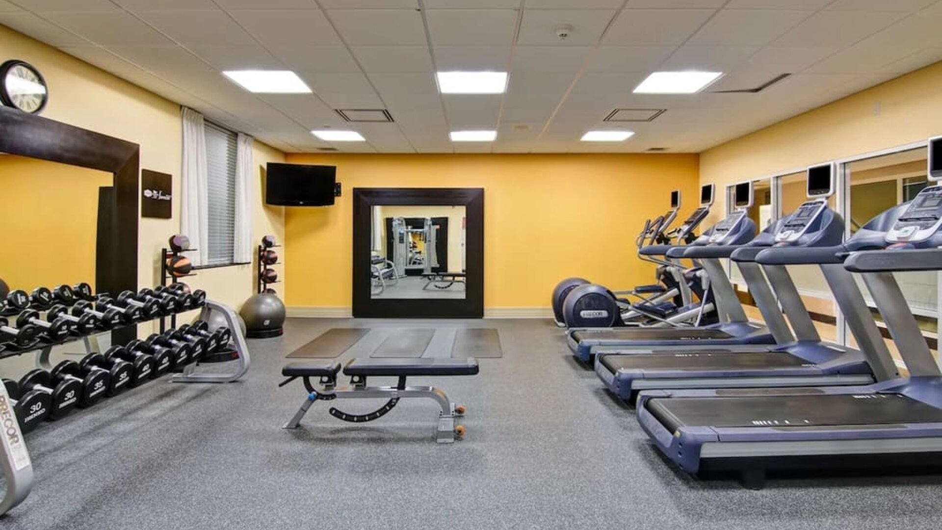 Fully equipped fitness center with treadmills and weights at the Hampton Inn by Hilton Toronto Airport Corporate Centre.