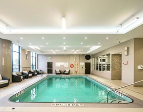 Relaxing indoor pool with lounge chairs at DoubleTree By Hilton Kitchener.