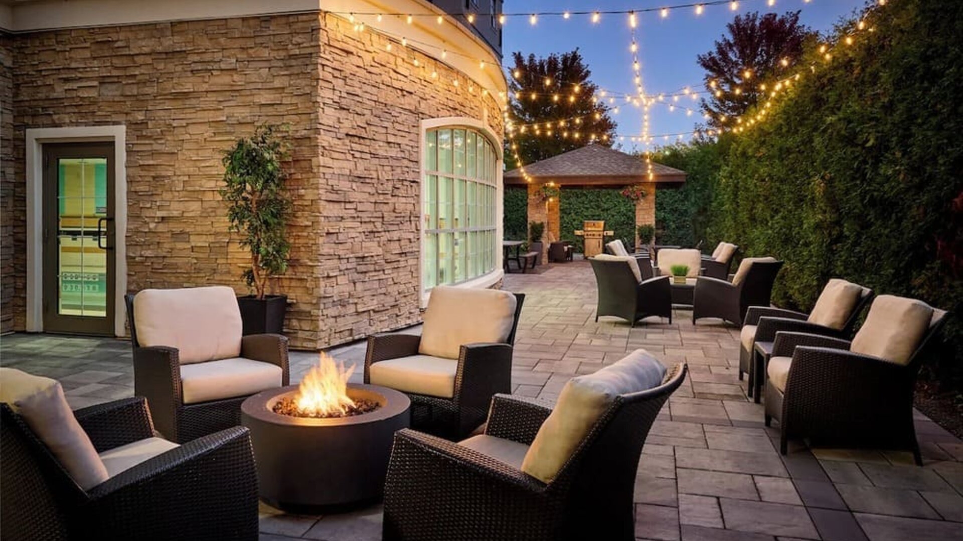Outdoor patio with lounge seating and fireplace  at Staybridge Suites Oakville-Burlington.