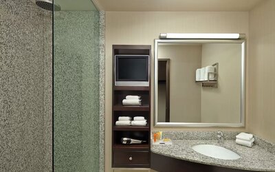 Guest bathroom with shower and free toiletries at Acclaim Hotel Calgary Airport.