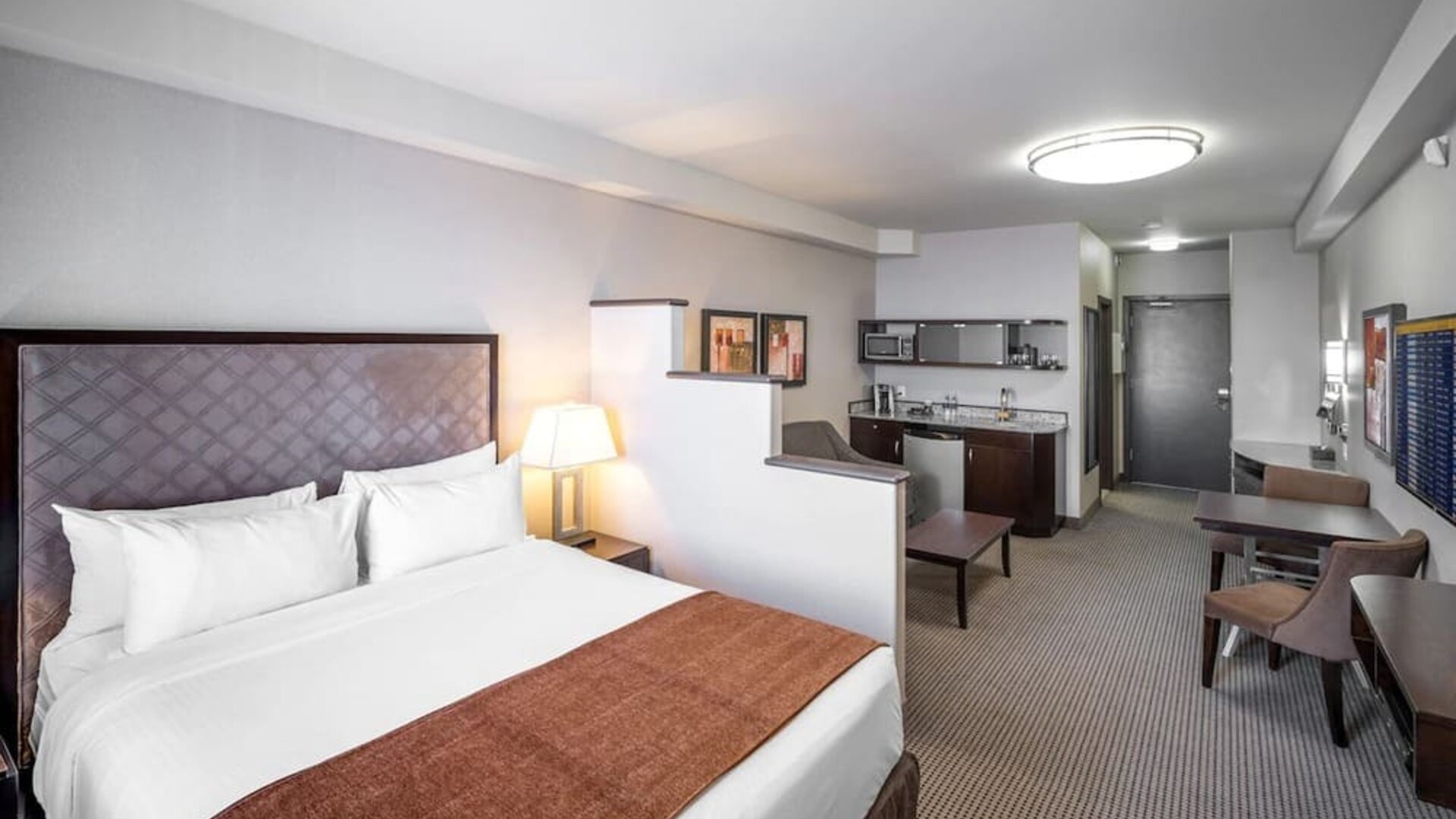 Day use studio suite with living area, workspace and in-room kitchen at Acclaim Hotel Calgary Airport.