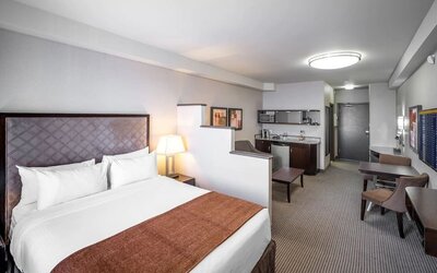 Day use studio suite with living area, workspace and in-room kitchen at Acclaim Hotel Calgary Airport.
