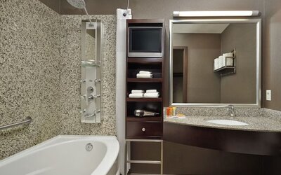 Private guest bathroom with tub, shower and free toiletries at Acclaim Hotel Calgary Airport.
