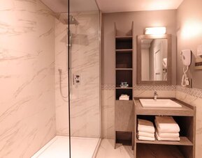 Guest bathroom with shower and free toiletries at Le Chabrol Hotel Et Suites.