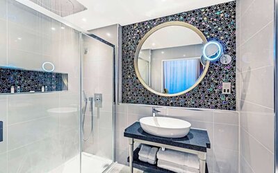 Guest bathroom with shower and free toiletries at Mercure Hotel London Hyde Park.