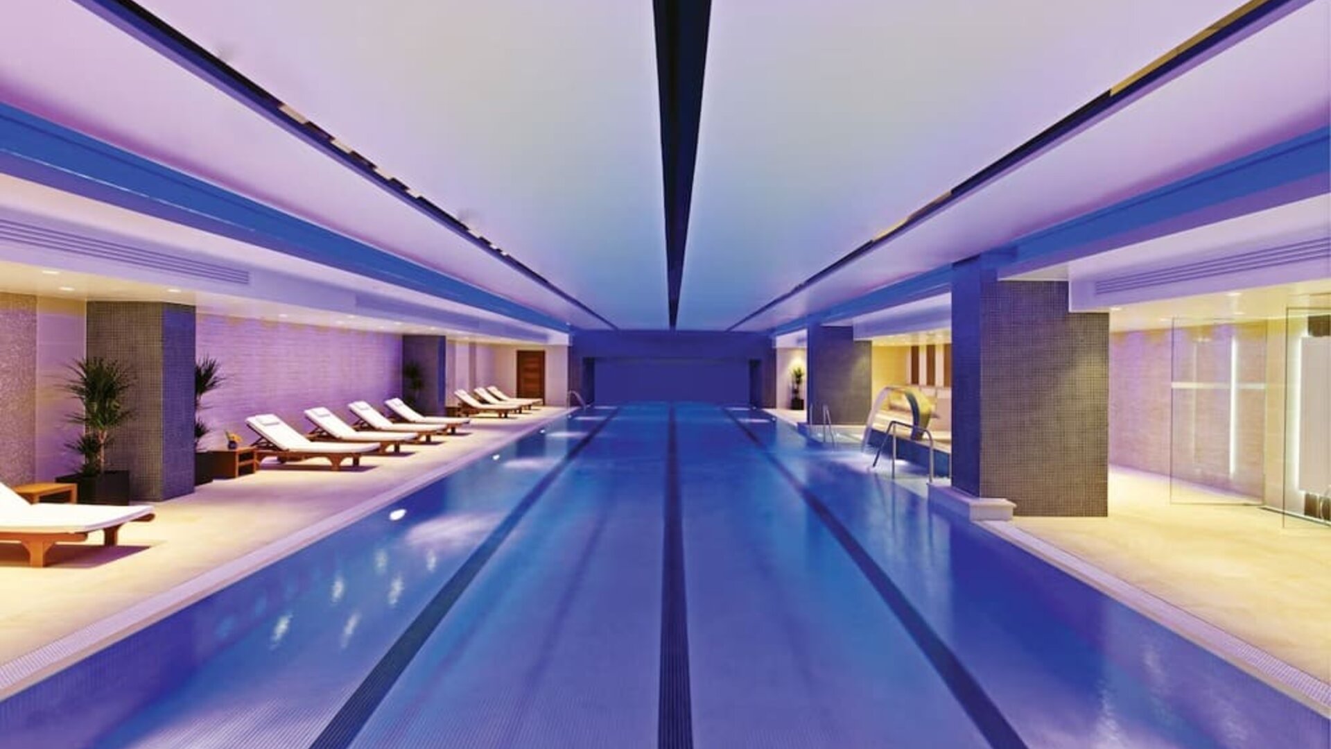 Relaxing indoor pool with lounge chairs at Leonardo Royal Hotel London Tower Bridge.