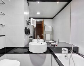 Private guest bathroom with separate shower and tub at Leonardo Royal Hotel London Tower Bridge.