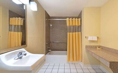 Guest bathroom with shower and tub at Days Inn By Wyndham San Antonio Northwest/Seaworld.