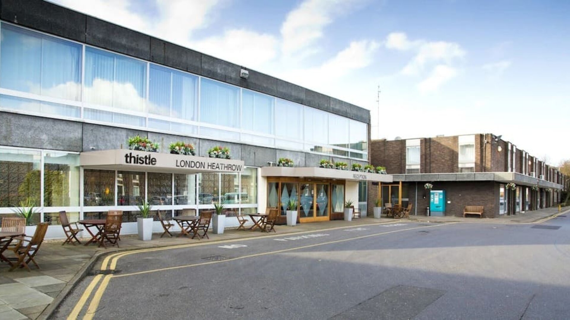 Hotel exterior with lounge seating at Thistle London Heathrow Terminal 5 Hotel.