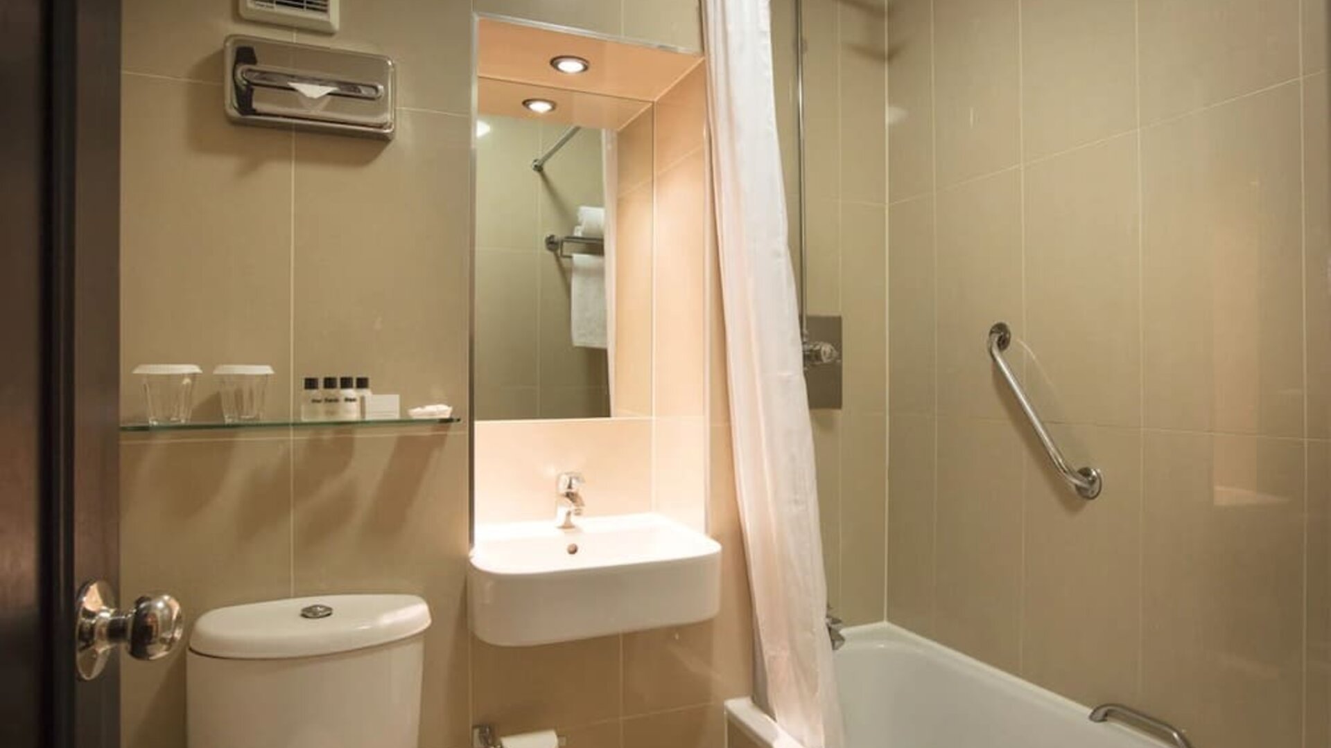 Guest bathroom with combined tub and shower at Thistle London Heathrow Terminal 5 Hotel.