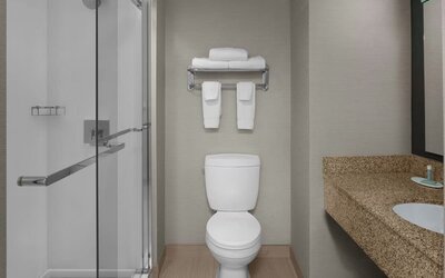 Guest bathroom with shower at Courtyard By Marriott Cypress Anaheim.