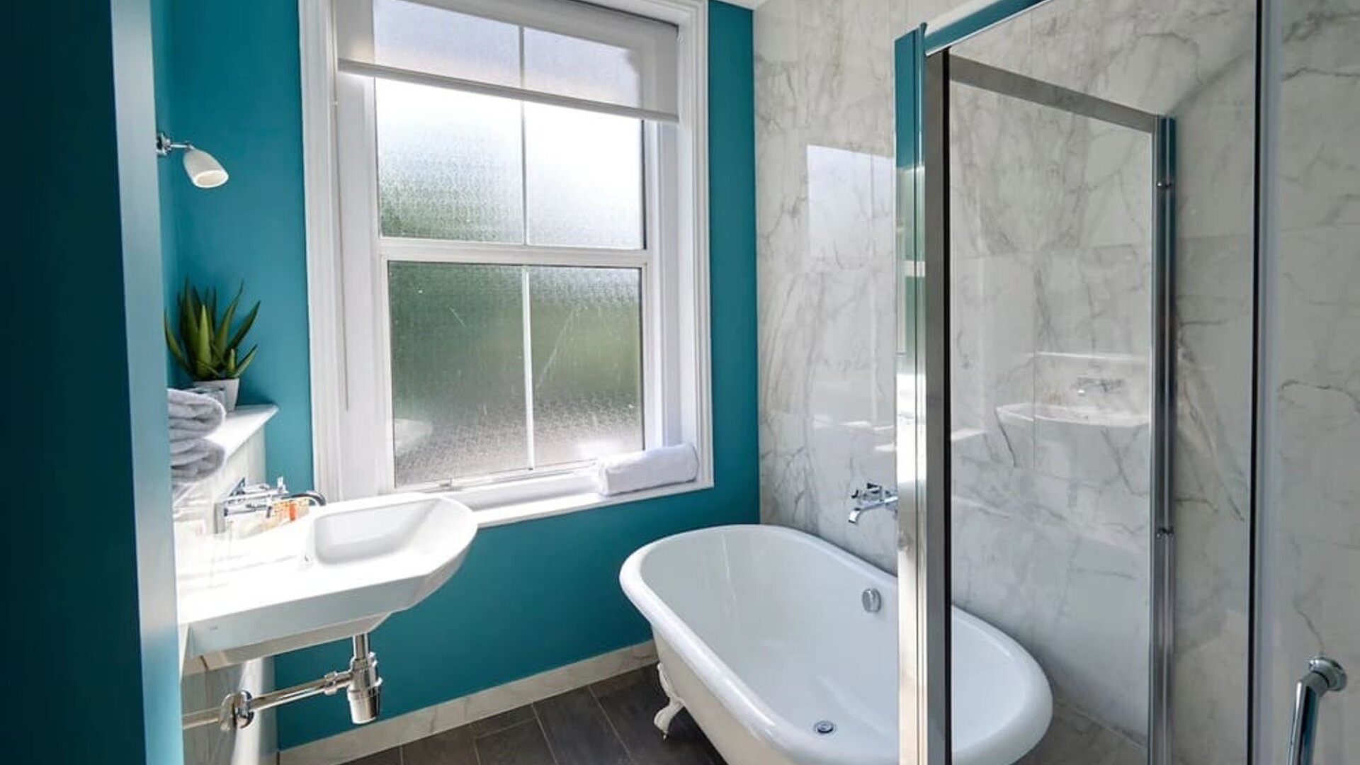 Private guest bathroom with shower and tub at The Lodge - Putney Hotel.