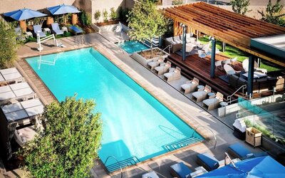 Refreshing outdoor pool surrounded by pool chairs at Hotel Nia, Autograph Collection.