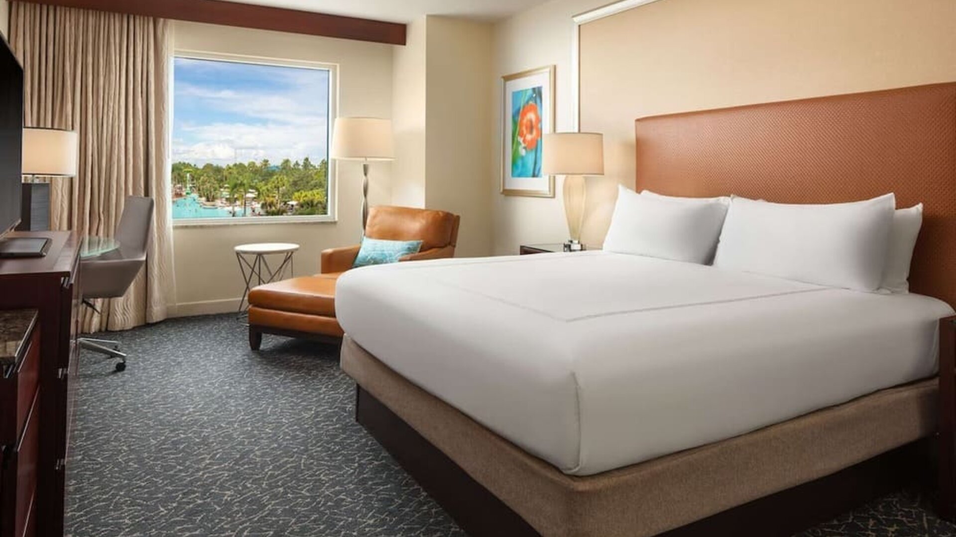 King room with TV, work desk, sofa and a great pool view at Hilton Orlando.