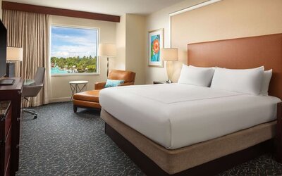 King room with TV, work desk, sofa and a great pool view at Hilton Orlando.