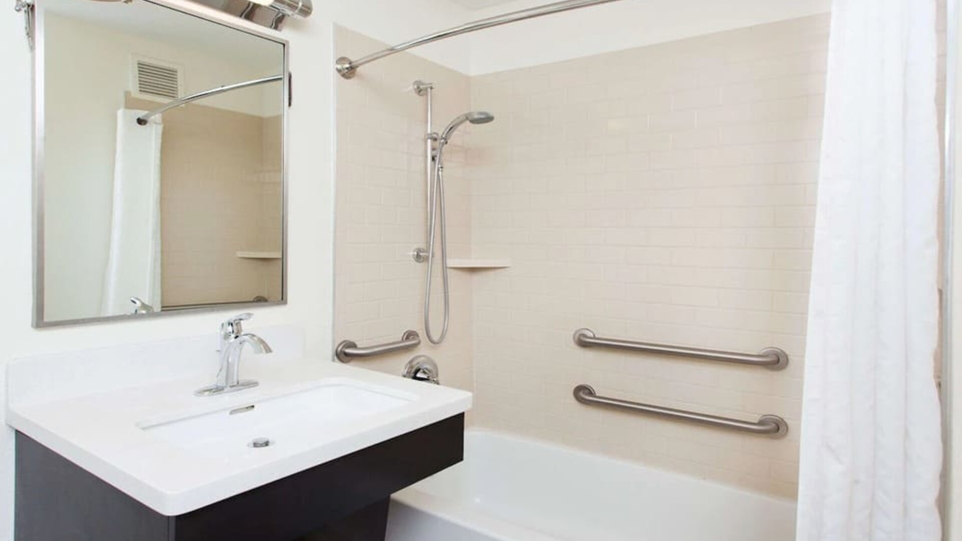 Private guest bathroom with combined shower and tub at Sonesta Simply Suites Dallas Las Colinas.