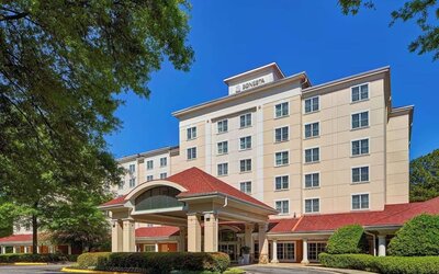 Sonesta Atlanta Airport South’s exterior features a covered entrance, well-kept greenery, and stylish red roof tiles.
