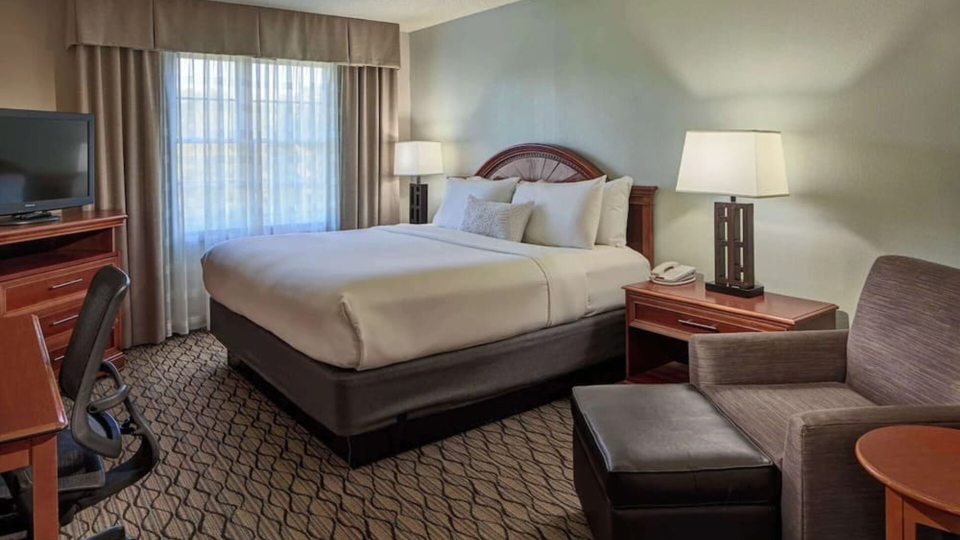 King bed with work desk and lounge seating at Sonesta Atlanta Airport South.