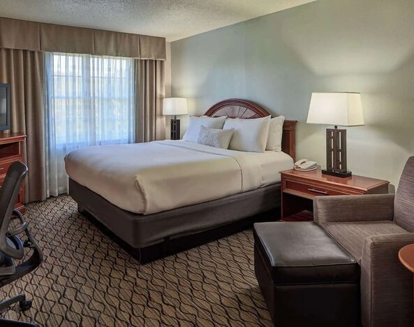 King bed with work desk and lounge seating at Sonesta Atlanta Airport South.