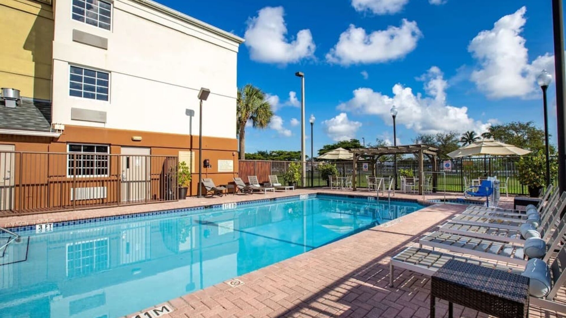 Outdoor pool with lounge chairs at Sonesta Simply Suites Miami Airport Doral.
