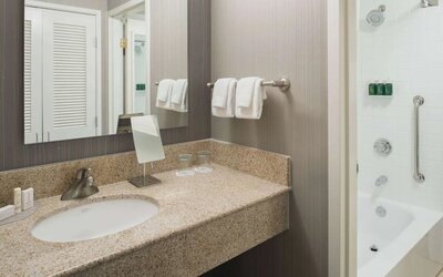 Private guest bathroom with combined shower/tub and free toiletries at Sonesta Select Seattle Bellevue Redmond.