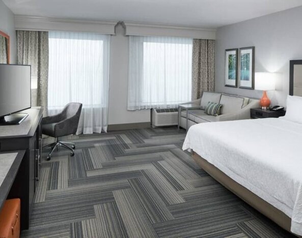 Spacious king bed room with work desk and sofa at Hampton Inn & Suites By Hilton Atlanta Perimeter Dunwoody.
