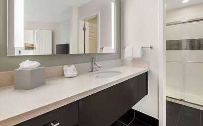 Private guest bathroom with shower and free toiletries at Sonesta ES Suites Dulles Airport.